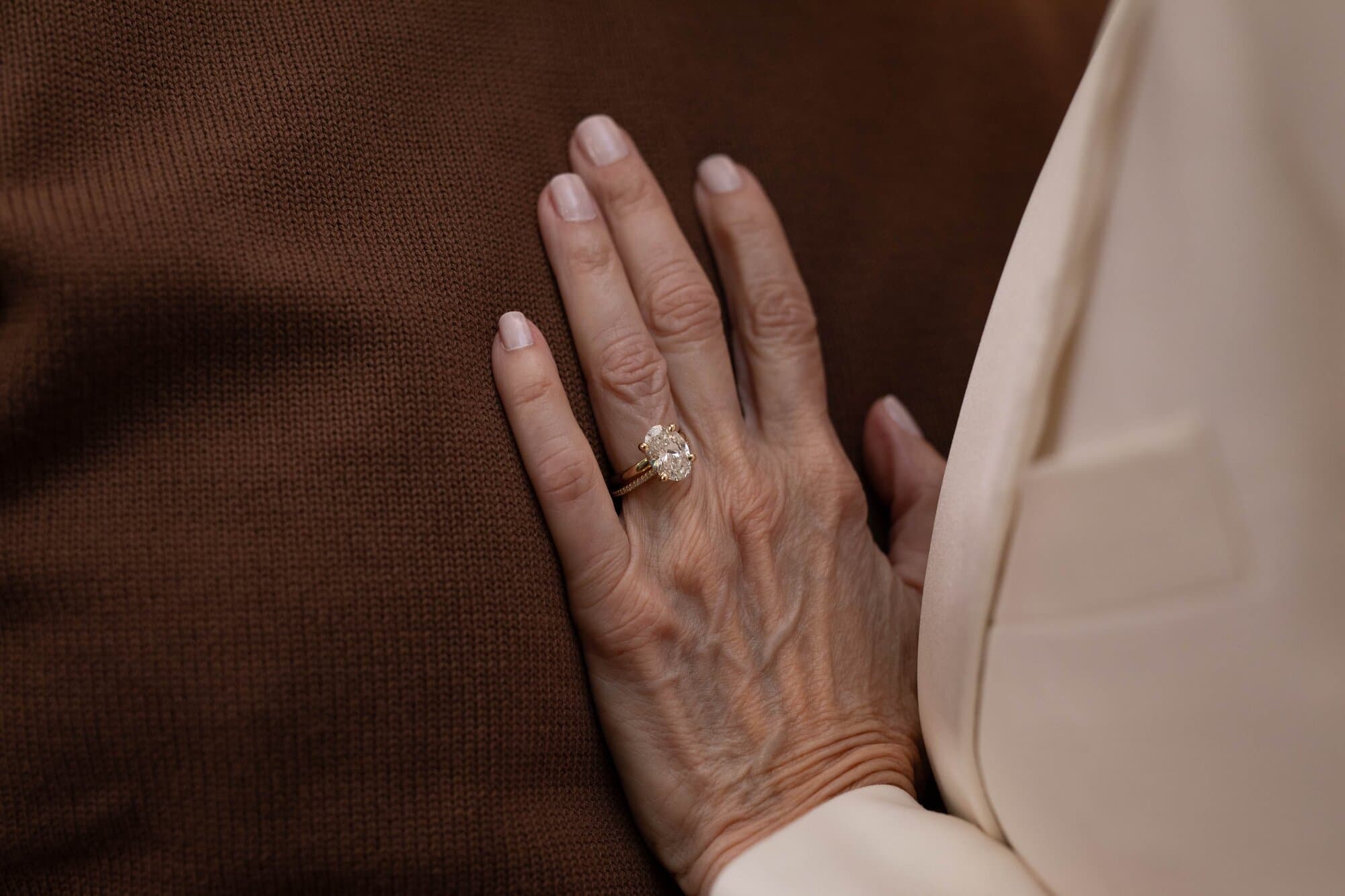 A couple embracing and showcasing their wedding jewelry.