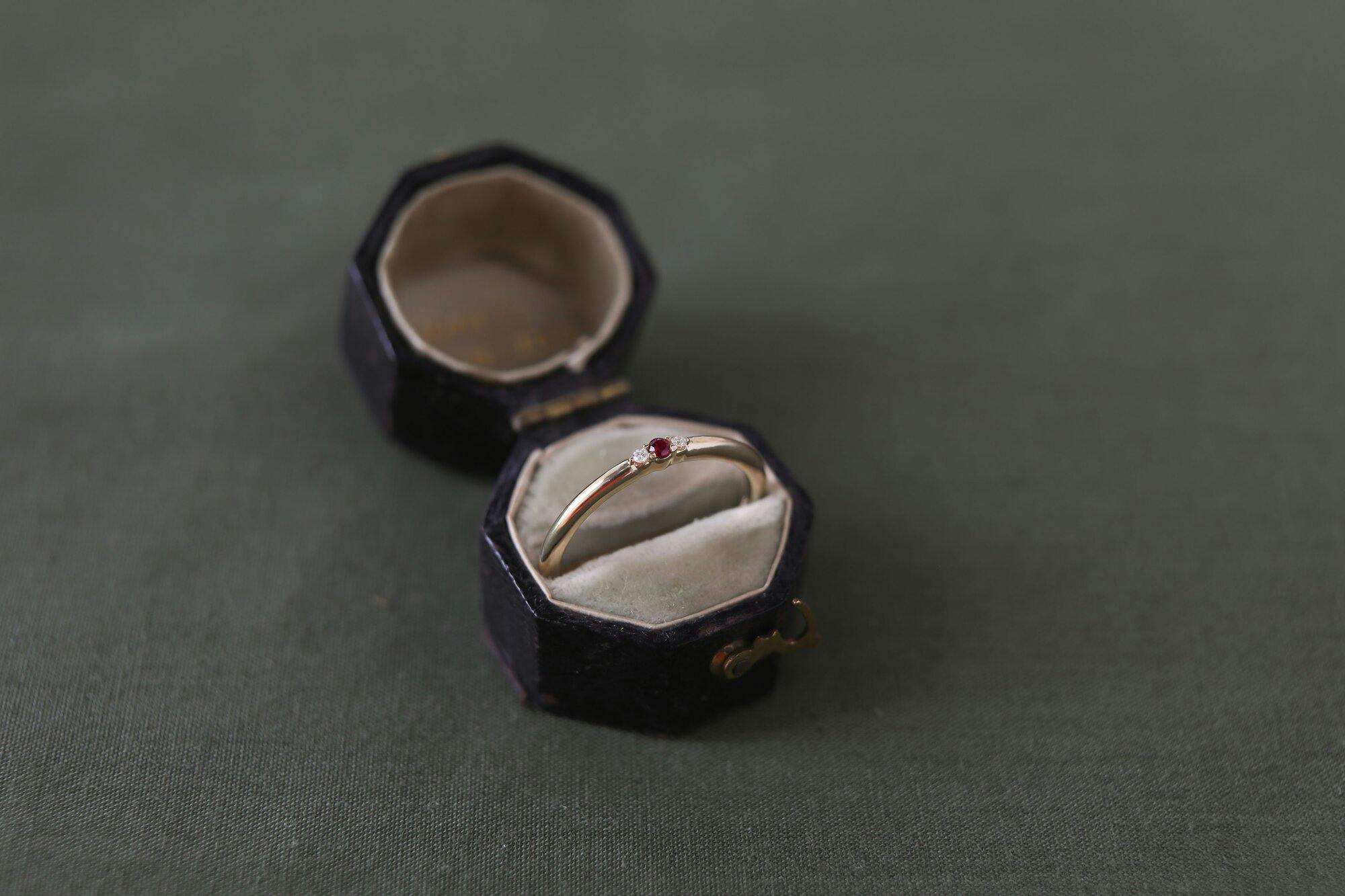 a picture of a gold band with a garnet stone in a ring box. 