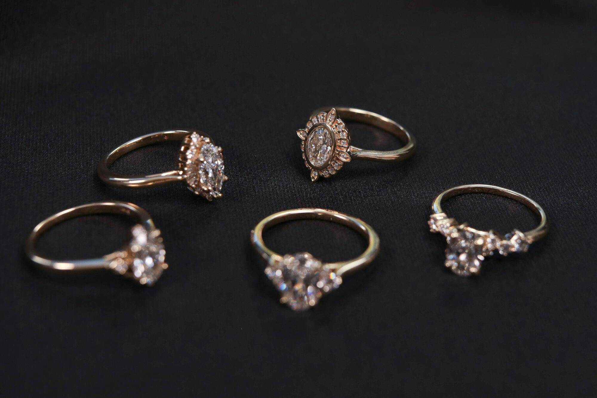 group shot of diamond engagement rings on a black fabric with one ring in focus and the rest in the background