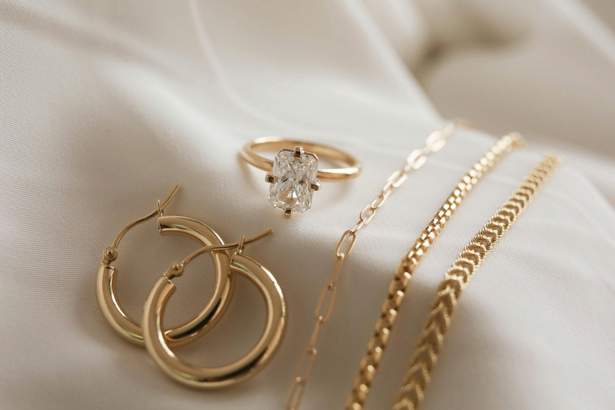 a group shot of a lab diamond ring with other gold jewelry like earrings and bracelets