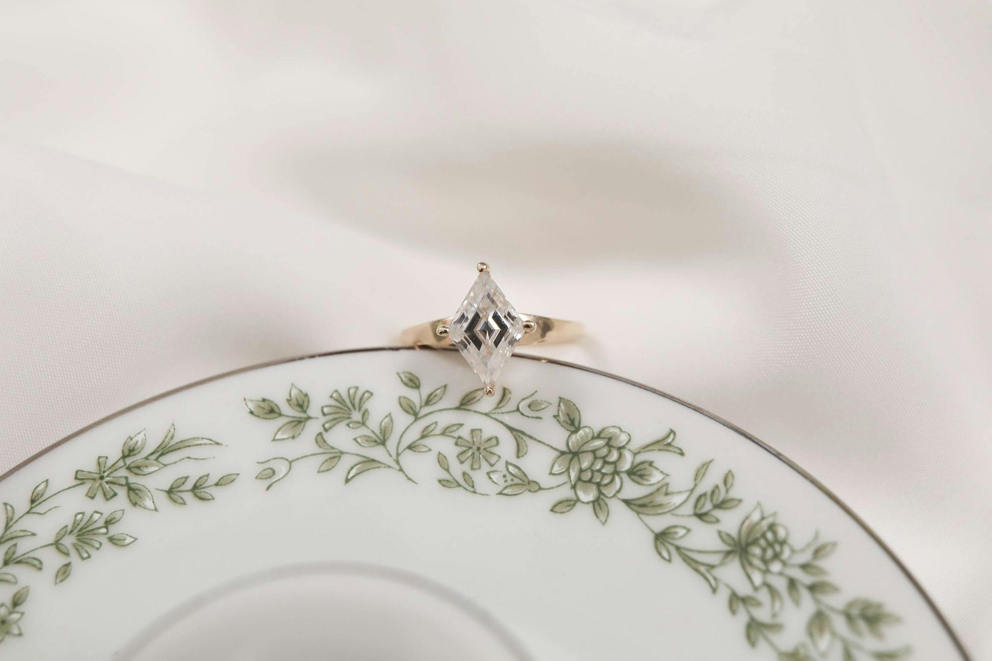 a photo of a lozenge cut engagement ring resting on a plate