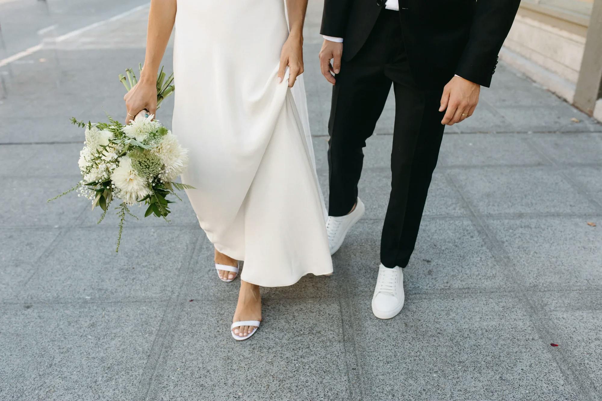Bride and groom walking with wedding bouquet.