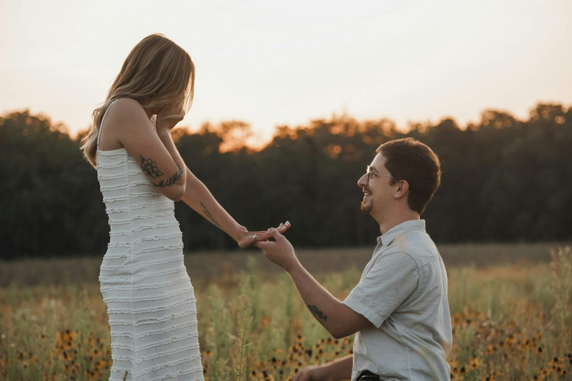 a man proposing to his girlfriend in a green field