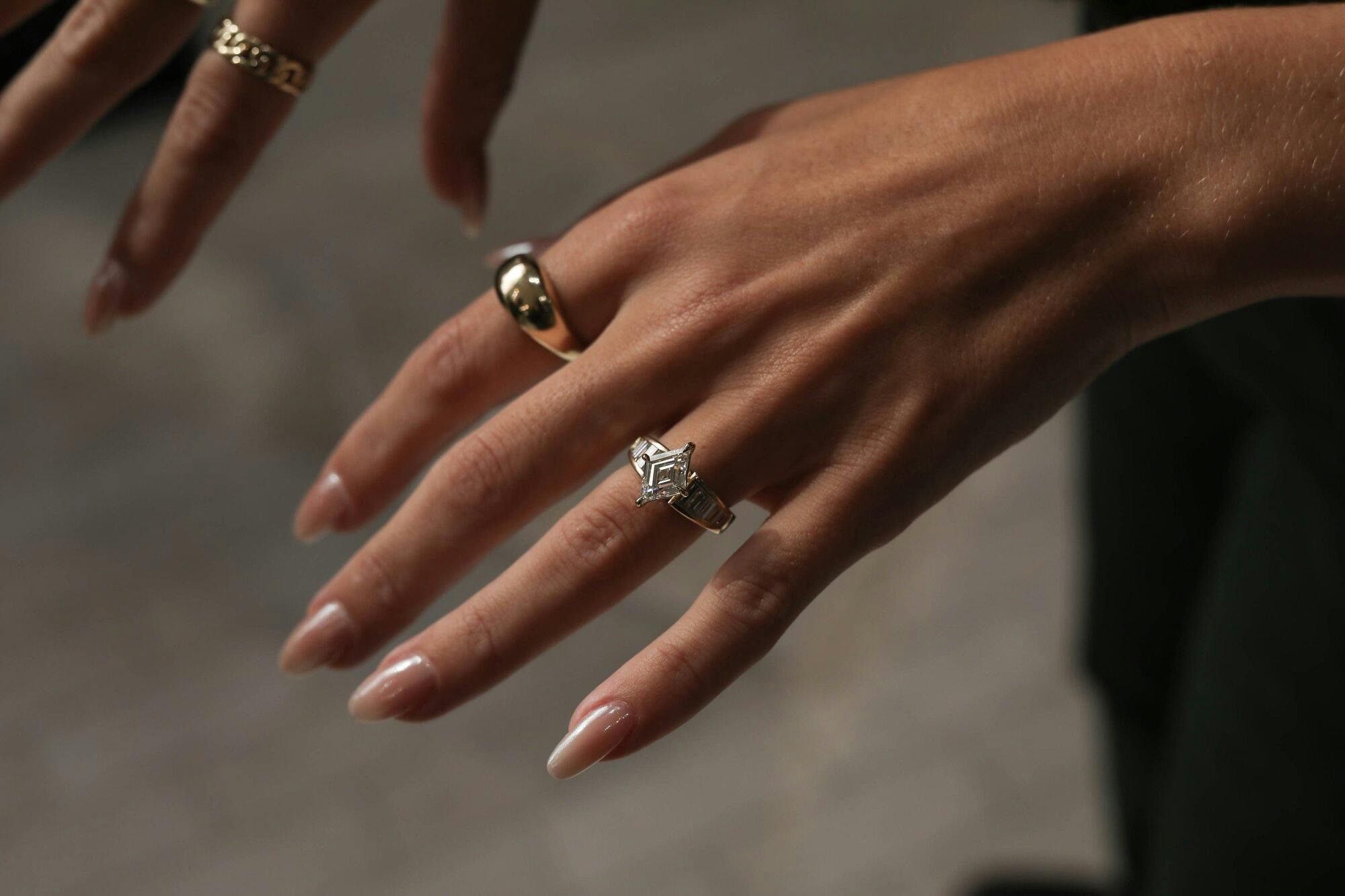 Hand wearing diamond engagement ring.