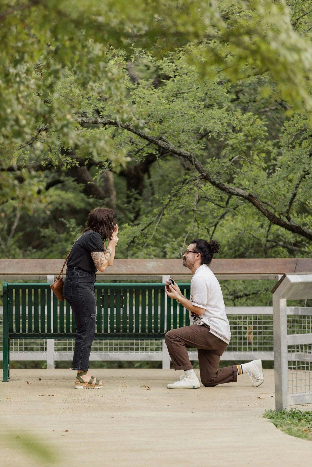 a man proposing to his girlfriend in a lush park