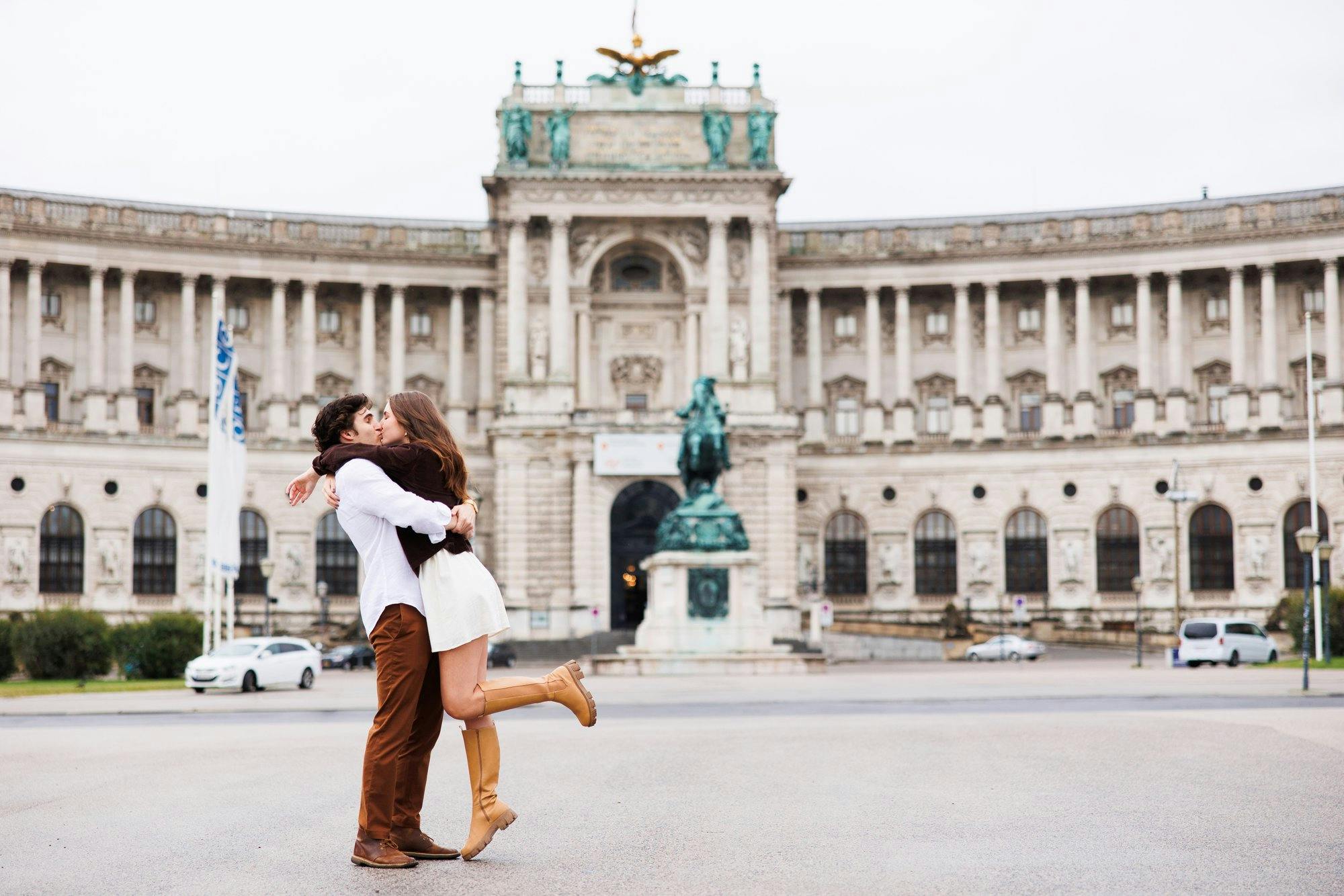 a couple kissing in front of a beautiful building