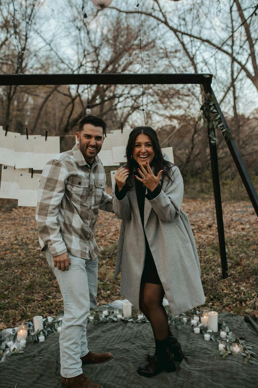 a picture of a couple in the woods during fall getting engaged