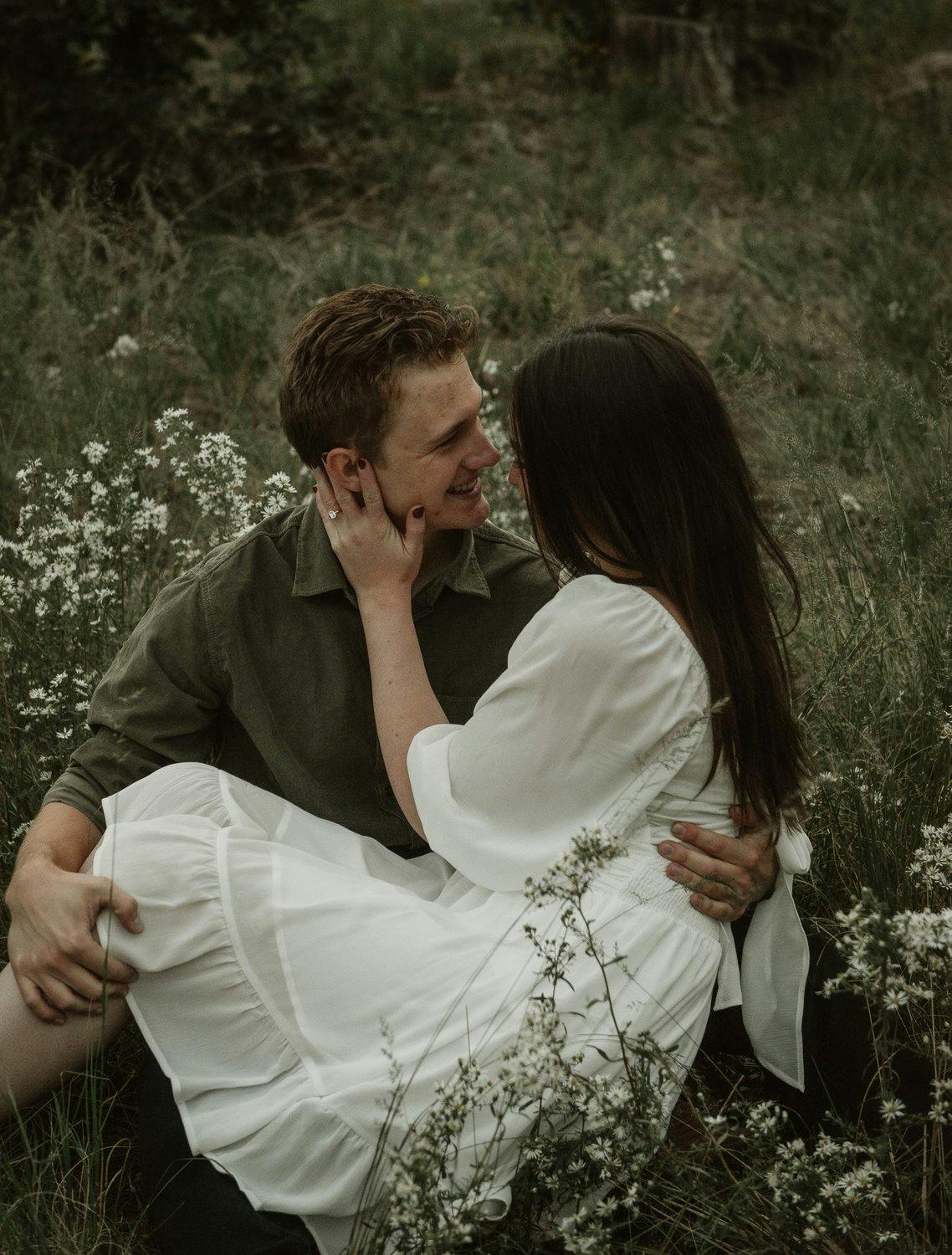 a young, engaged couple posing in a dandelion field